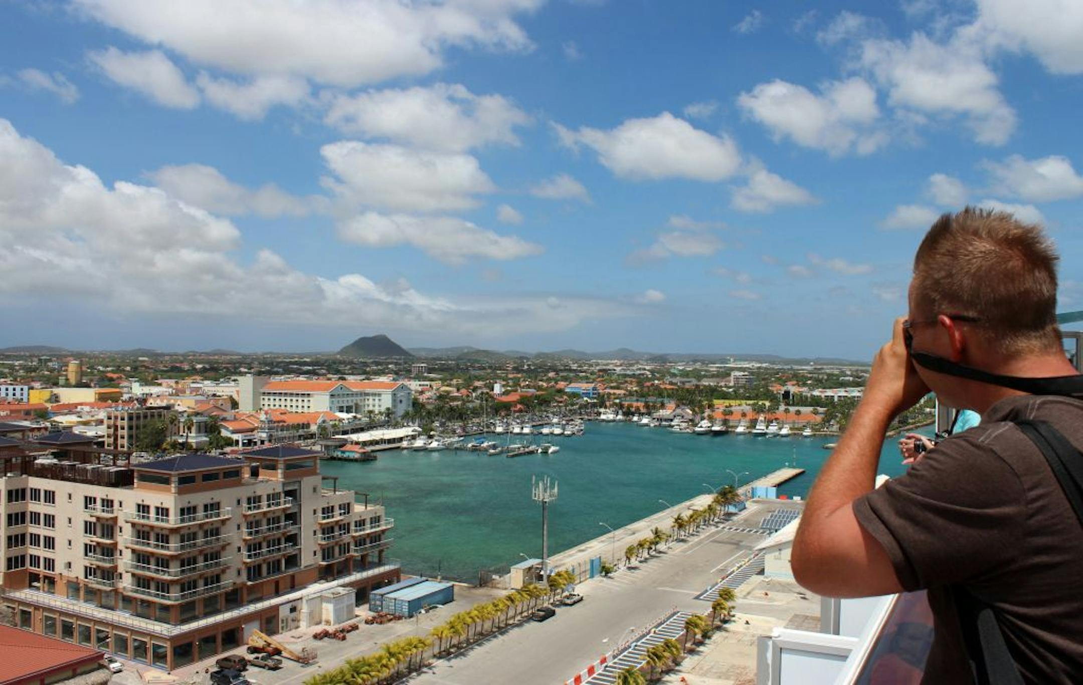 Passengers stand at the rails as the Carnival Valor sails into Aruba.