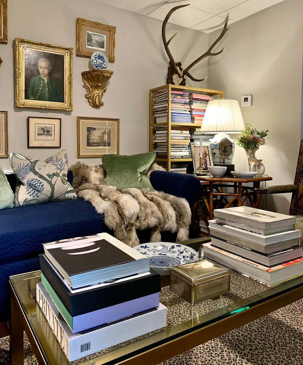 The brass and glass coffee table holds favorite books while allowing the leopard rug to make its presence known in Jim Miller’s chic and charming home. Scottish roebuck antlers draw the eye up and add height.