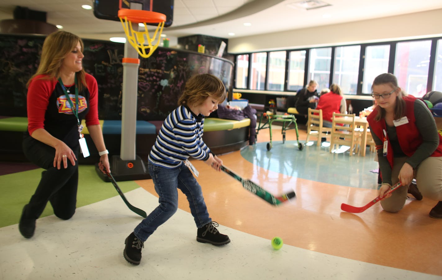 Stephanie Smith, Child Life Specialist, and volunteer Carly Cich played floor hockey with Liam Horneman, 3, as he pretended to be Sidney Crosby. ] (KYNDELL HARKNESS/STAR TRIBUNE) kyndell.harkness@startribune.com Stephanie Smith, Child Life Specialist at Children's Hospital has taken the Life is Good training works with kids. This was shot Wednesday, March 1, 2017 at Children's Hospital in St. Paul, Min.