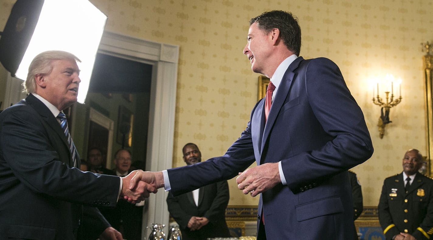 James Comey, the director of the FBI, shakes hands with President Donald Trump at a reception for law enforcement officers and first responders who helped at the inauguration, in the Blue Room of the White House in Washington, Jan. 22, 2017. (Al Drago/The New York Times) ORG XMIT: MIN2017012408343008