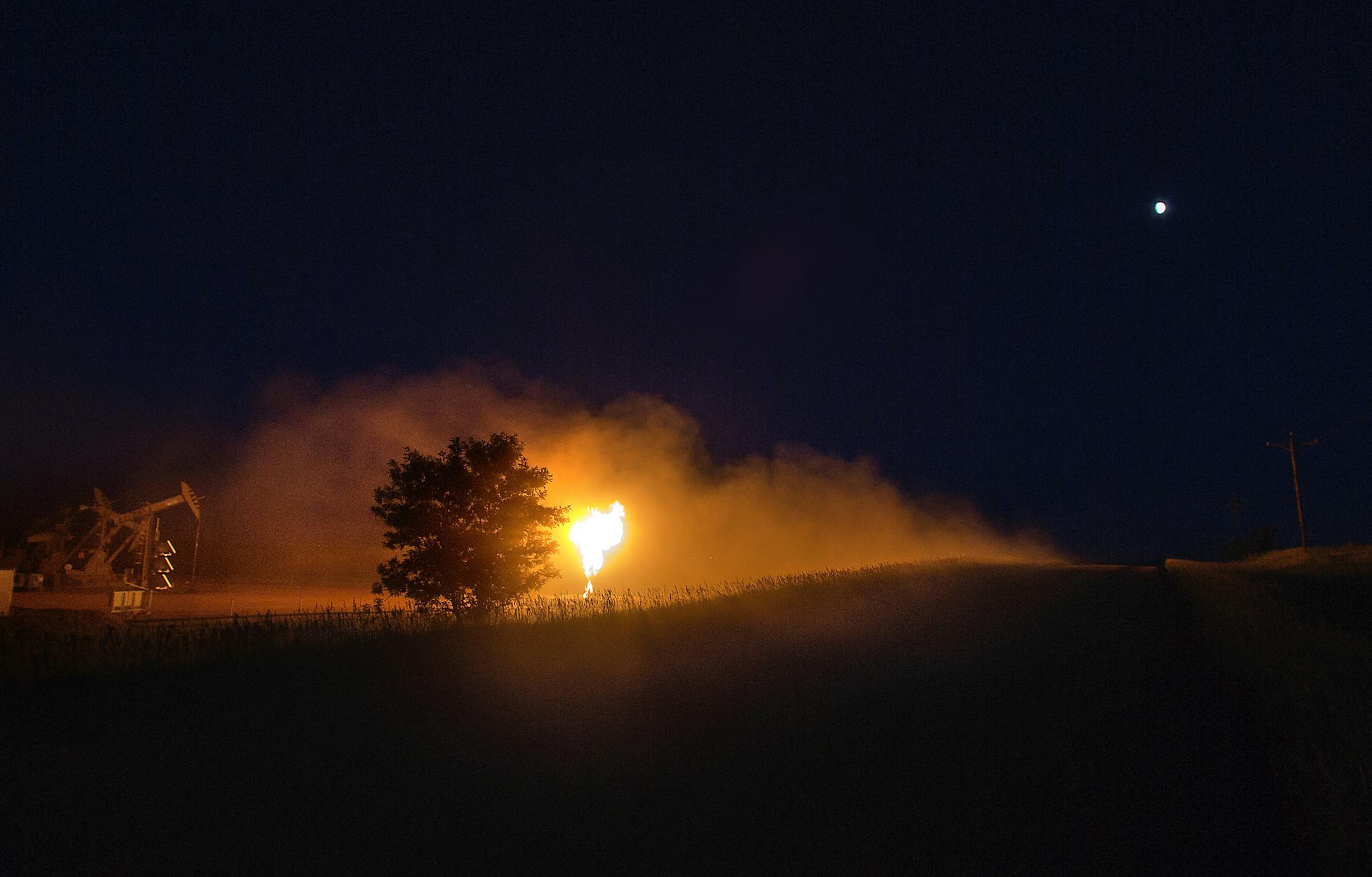 A cloud of dust raised by a passing oil truck was dramatically illuminated by the bright light emitted by the flame of a flare stack on an oil pad near Watford City. ] (JIM GEHRZ/STAR TRIBUNE) / September 26, 2013, Watford City, ND ‚Äì BACKGROUND INFORMATION- PHOTOS FOR USE IN FIRST PART OF NORTH DAKOTA OIL BOOM PROJECT: Dozens of drilling rigs dot the North Dakota landscape in the Williston Basin and the Bakken Oil Formation. Once the rigs drill holes, several miles deep and th