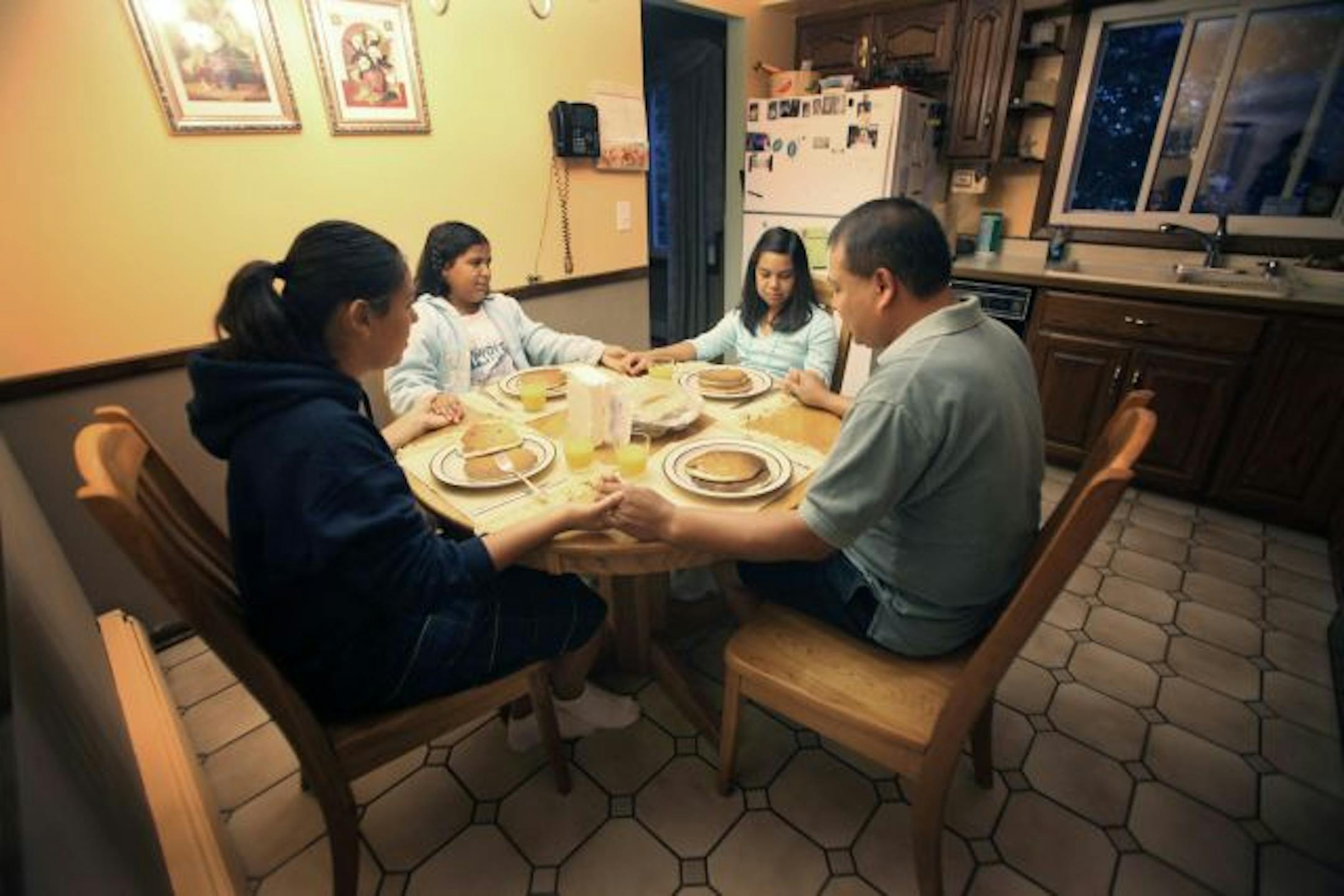 Oscar Gomez of Burnsville prayed with his daughters, from left, Liliana, 13, Catarina, 10, and Rosa, 8, before breakfast. His wife has dinner with the girls