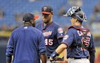 Minnesota Twins pitching coach Garvin Alston, left, and catcher Jason Castro talk with starter Phil Hughes, center, on the mound during the first inni