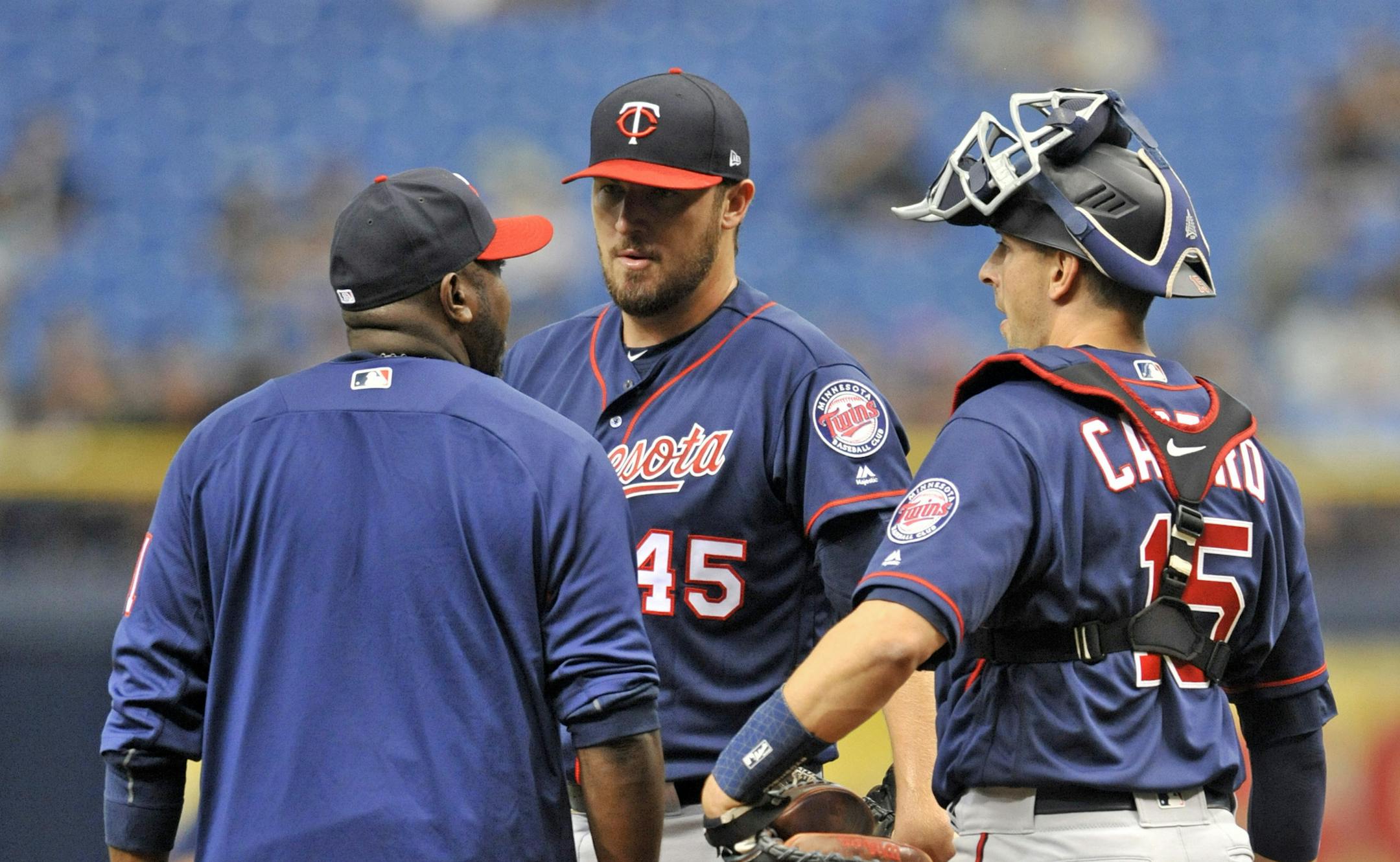 Minnesota Twins pitching coach Garvin Alston, left, and catcher Jason Castro talk with starter Phil Hughes, center, on the mound during the first inning of a baseball game against the Tampa Bay Rays Sunday, April 22, 2018, in St. Petersburg, Fla. (AP Photo/Steve Nesius)