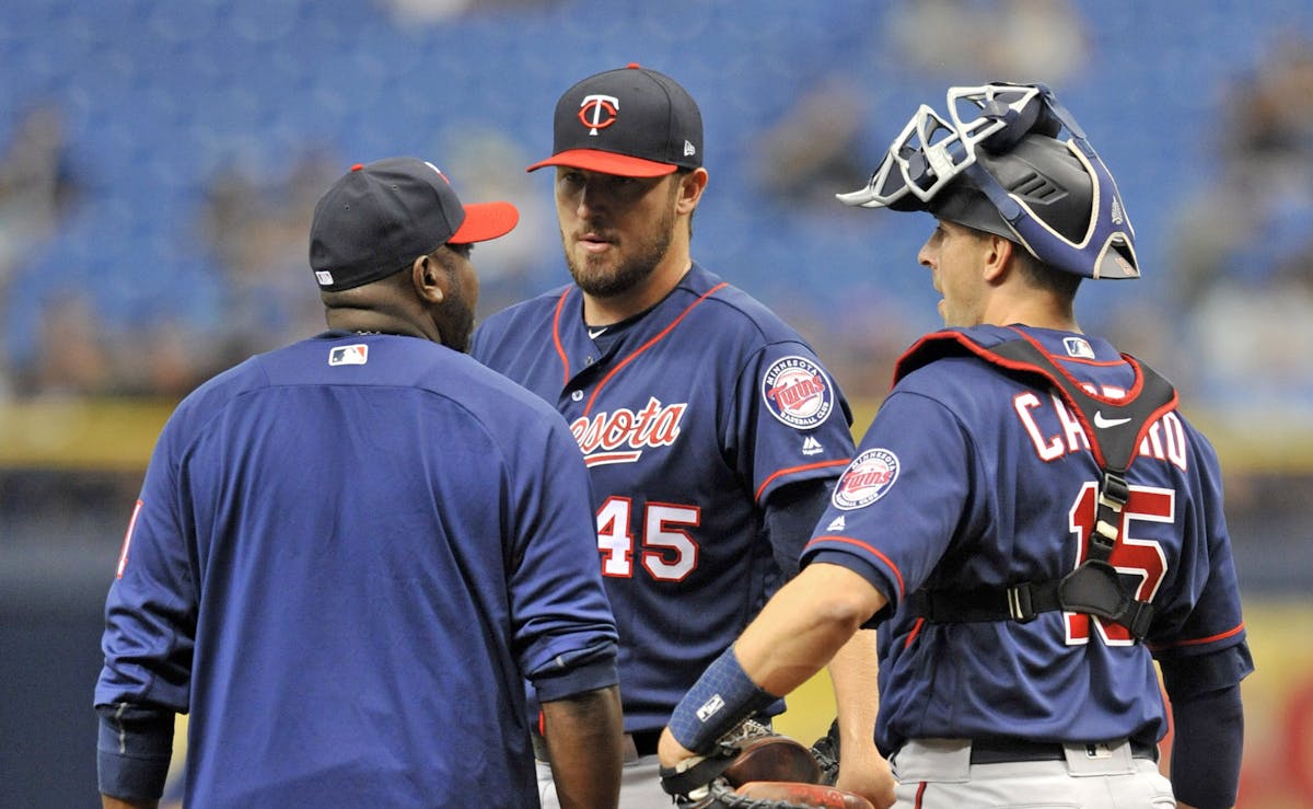 Minnesota Twins pitching coach Garvin Alston, left, and catcher Jason Castro talk with starter Phil Hughes, center, on the mound during the first inni