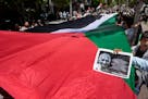 Activists carry a large Palestinian flag during a mass ceremony to commemorate the Nakba Day, Arabic for catastrophe, in the West Bank city of Ramalla