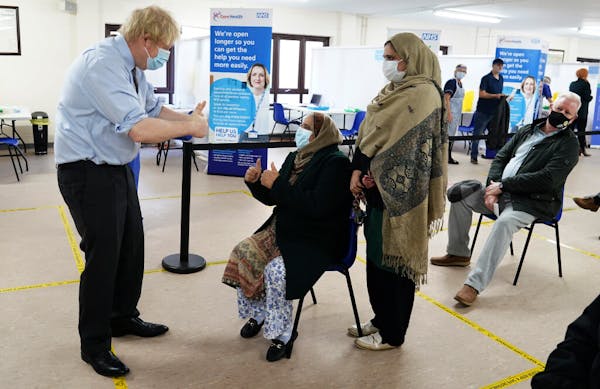 Britain’s Prime Minister Boris Johnson gives a thumbs up to patients after they received the vaccine as he visits a COVID-19 vaccination centre i