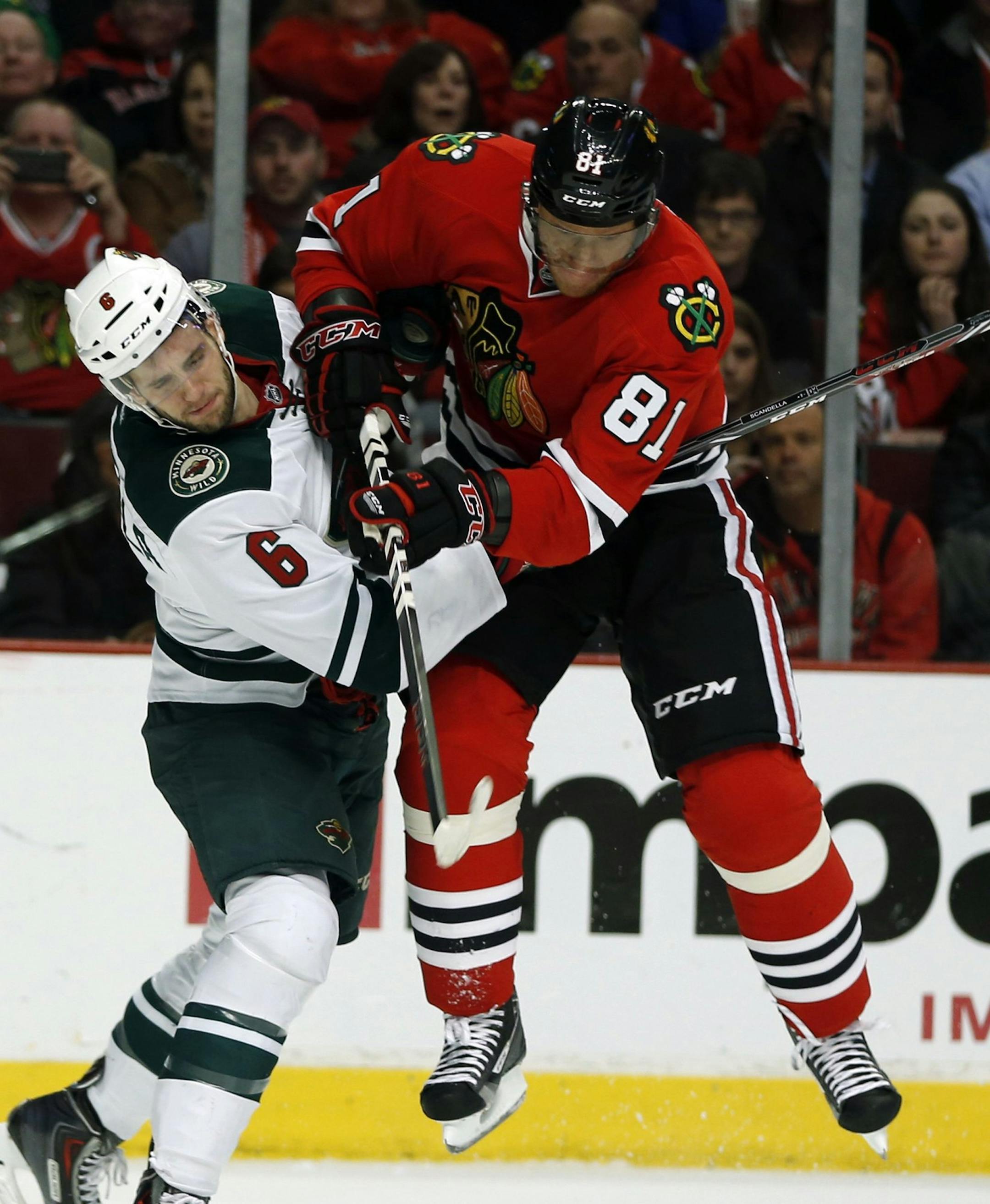 The Chicago Blackhawks' Marian Hossa (81) and the Minnesota Wild's Marco Scandella (6) battle for the puck in the first period at United Center in Chicago on Thursday, April 3, 2014. (Scott Strazzante/Chicago Tribune/MCT)
