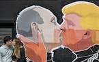 A couple kisses in front of graffiti depicting Russian President Vladimir Putin, left, and Republican presidential candidate Donald Trump, on the wall