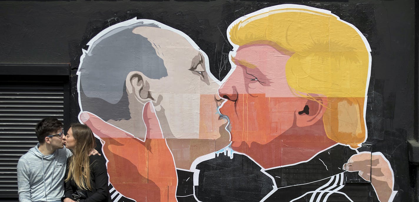 A couple kisses in front of graffiti depicting Russian President Vladimir Putin, left, and Republican presidential candidate Donald Trump, on the walls of a bar in the old town in Vilnius, Lithuania, Saturday, May 14, 2016. (AP Photo/Mindaugas Kulbis) ORG XMIT: MIN2016051415440030 ORG XMIT: MIN1607271118101001