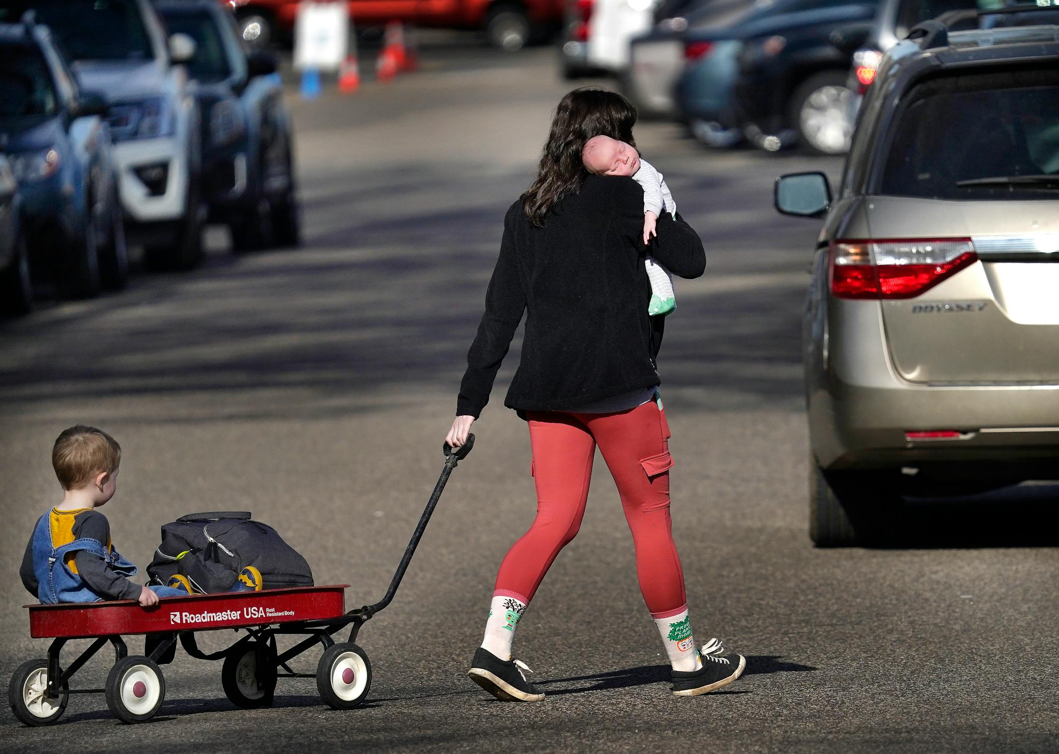Kelsey Drews of Roseville holds son Clark, 5 weeks, while pulling Bruce, 2, in a wagon as they headed for the start of the Friends School of Minnesota fundraiser plant sale.