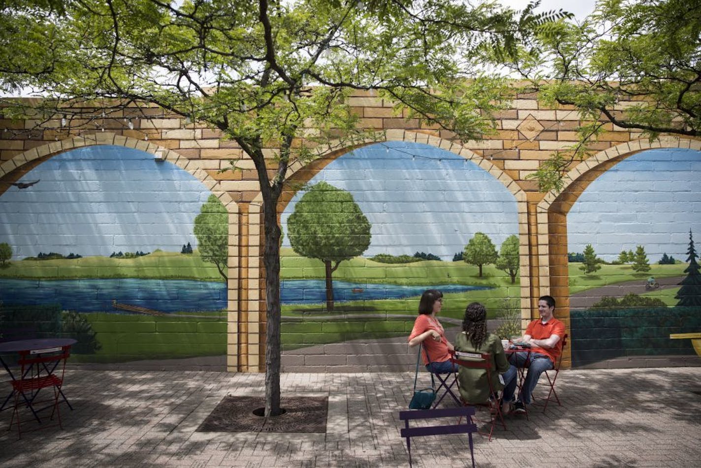 Ella Rasp, Rachel Auerbach and Kyle Flanegin took a donut break in a plaza with a mural in downtown Robbinsdale, Minn., on June 30, 2017.