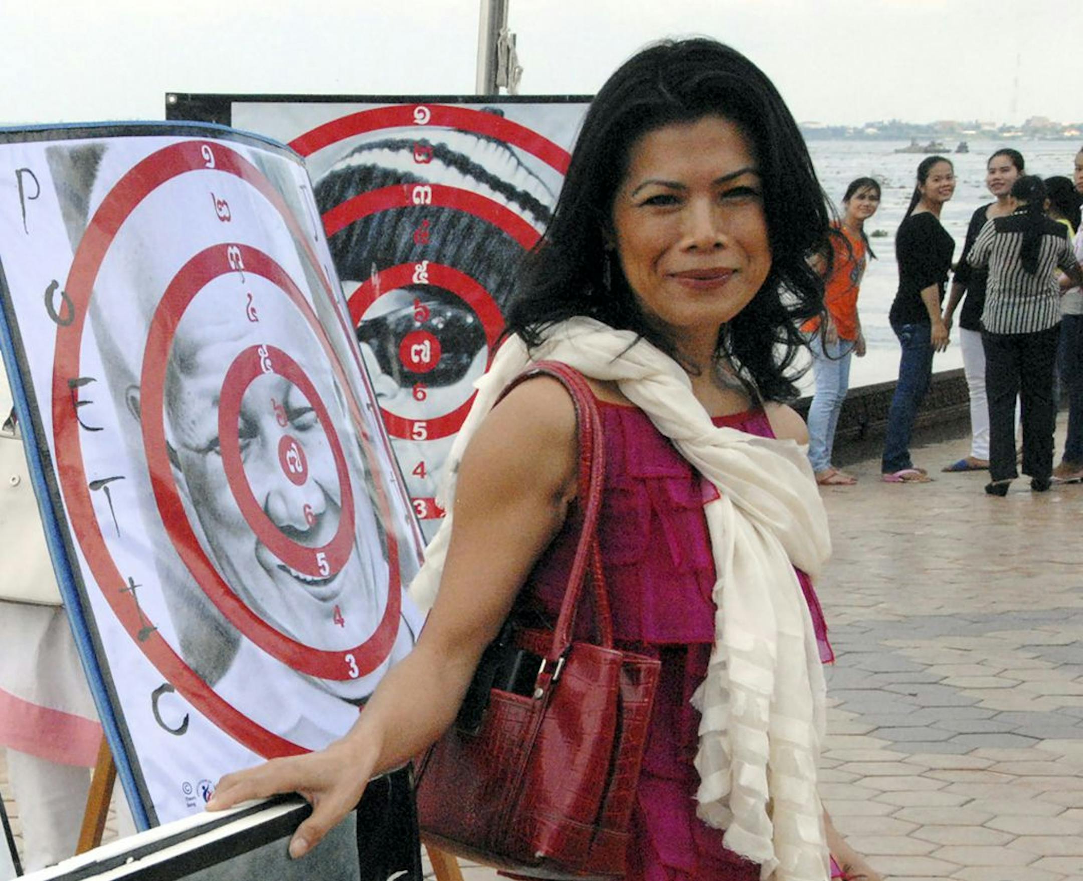In this Nov. 18, 2012, photo, activist Theary Seng poses with dart board posters during a protest in Phnom Penh, Cambodia. Activist and lawyer Theary Seng, is one of dozens of people have been targeted by Cambodian government in its most severe legal offensive against its political opponents in three years.