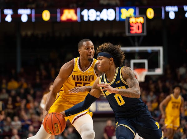 Michigan guard Dug McDaniel (0) stole the ball from Gophers guard Ta’lon Cooper (55) during Thursday’s game.