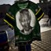 A South African man, right, walks past a T-shirt bearing the image of former South African President Nelson Mandela displayed for sale by a vendor, no