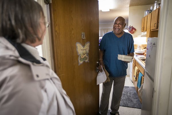 Tommy Holmes smiles and chats with Linda Brady after receiving his meals at his home in Hamilton Manor in 2018 from Community Emergency Services (CES)
