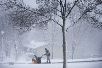 A man runs a snowblowers to clear his driveway during an early spring snowstorm in Lakeville.