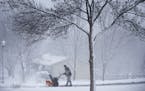 A man runs a snowblowers to clear his driveway during an early spring snowstorm in Lakeville.
