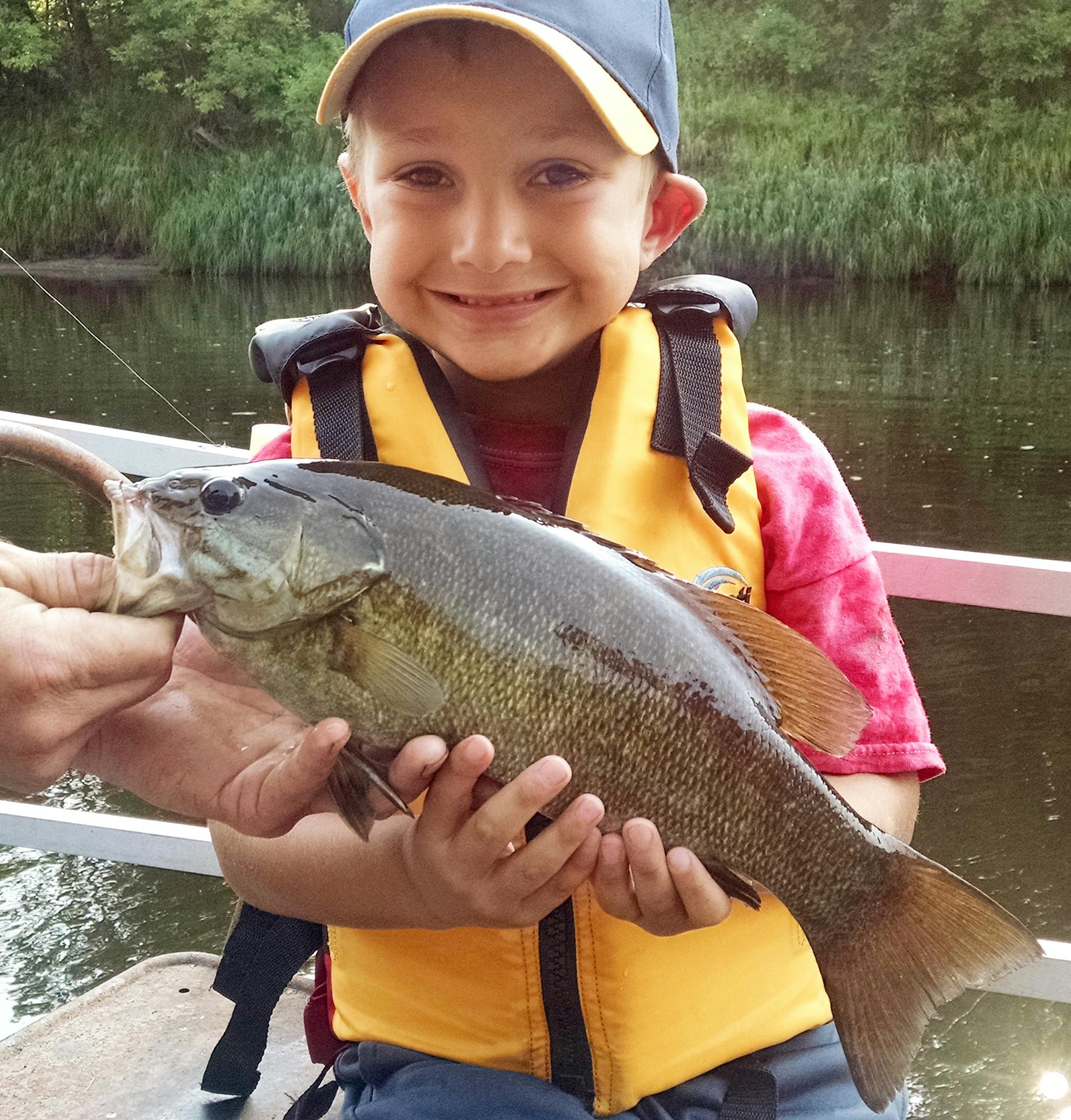 FIRST ONE Forrest Swartz, 6, of Minneapolis caught his first fish, a smallmouth bass, at his Grandpa's house on the St. Louis River north of Floodwood. He landed this one mostly by himself, with a little help from Dad. It put up quite a fight, jumping out of the water three times. The bass was released.