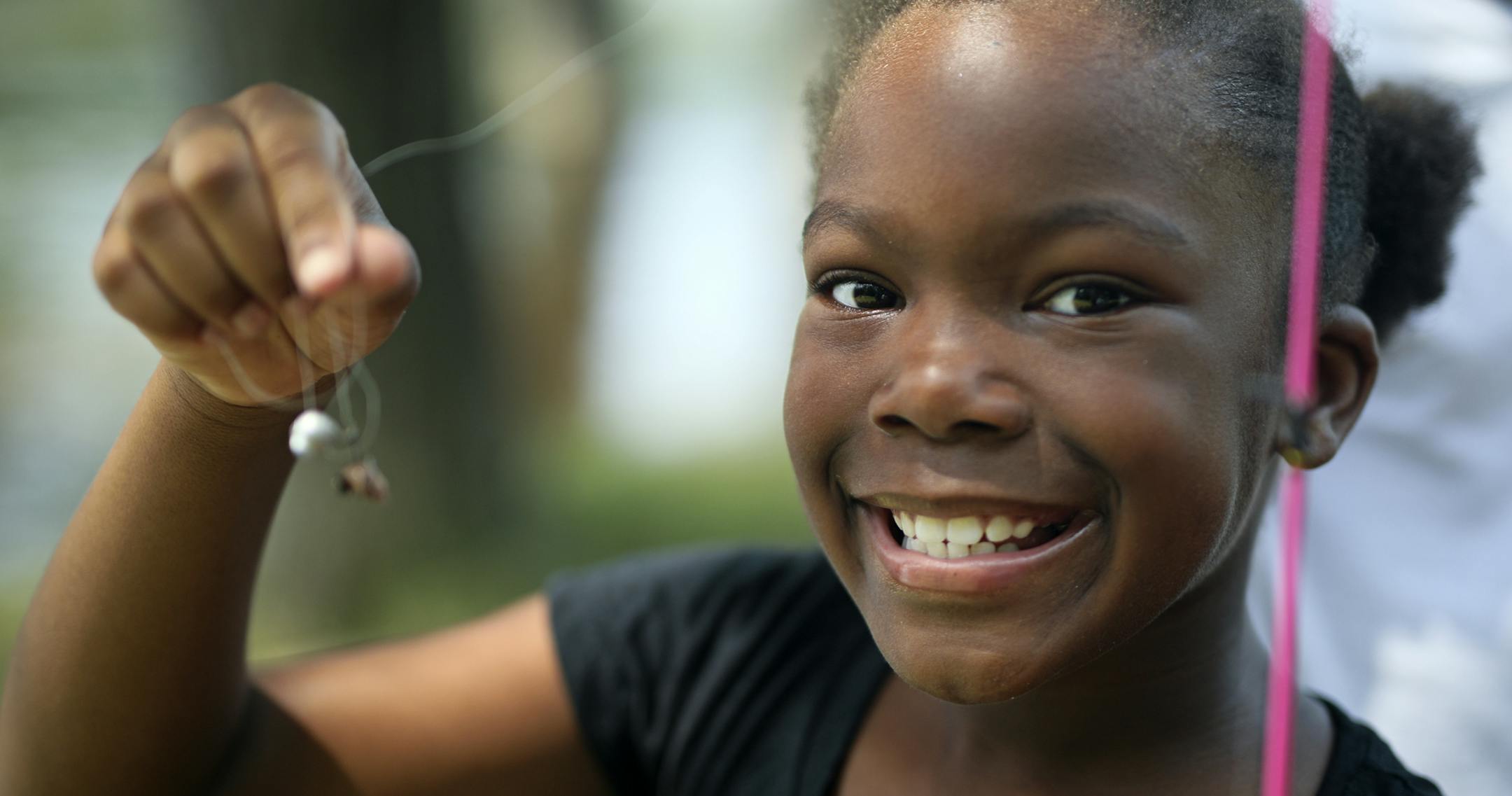 Zadaisa Brooks, 9, smiles before baiting her hook to go fishing for the first time at Hidden Falls Regional Park.