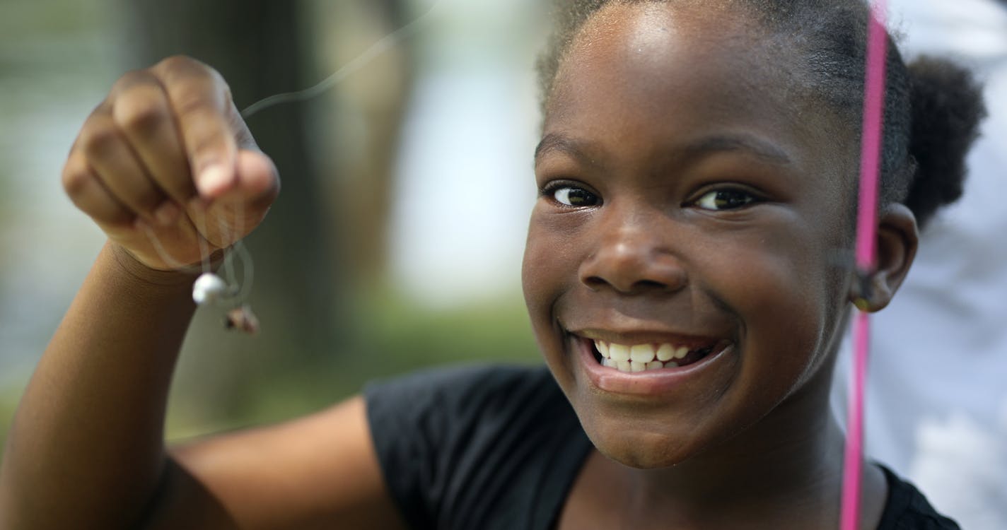 Zadaisa Brooks, 9, smiles before baiting her hook to go fishing for the first time at Hidden Falls Regional Park.