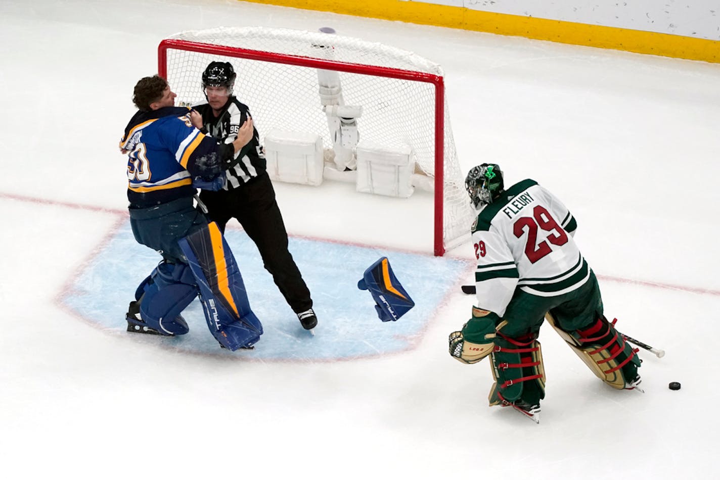 St. Louis Blues goaltender Jordan Binnington, left, is held back from fighting Minnesota Wild goaltender Marc-Andre Fleury (29).