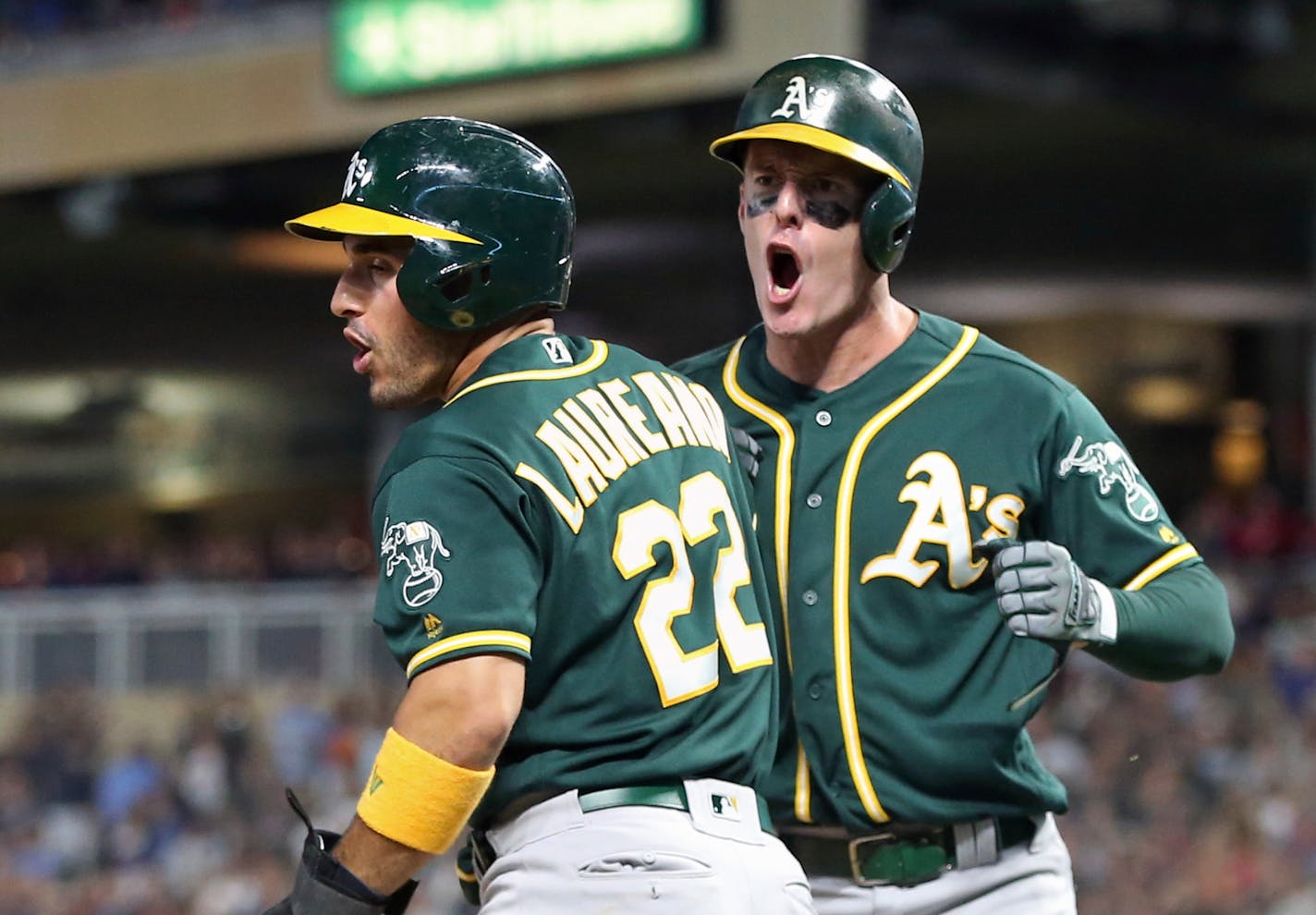 Oakland Athletics' Ramon Laureano, left, and Mark Canha celebrate after they scored on a two-run double by Chris Davis off Minnesota Twins relief pitcher Taylor Rogers in the ninth inning of a baseball game Saturday, July 20, 2019, in Minneapolis. The Athletics won 5-4. (AP Photo/Jim Mone)