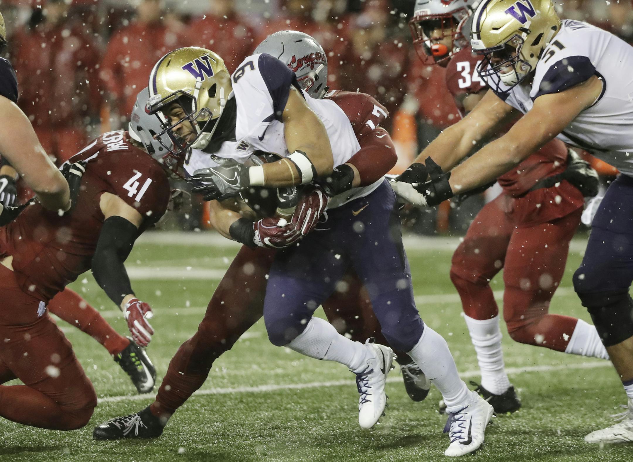Washington running back Myles Gaskin, center, is tackled by Washington State linebacker Peyton Pelluer as he rushes during the first half of an NCAA college football game, Friday, Nov. 23, 2018, in Pullman, Wash. (AP Photo/Ted S. Warren)