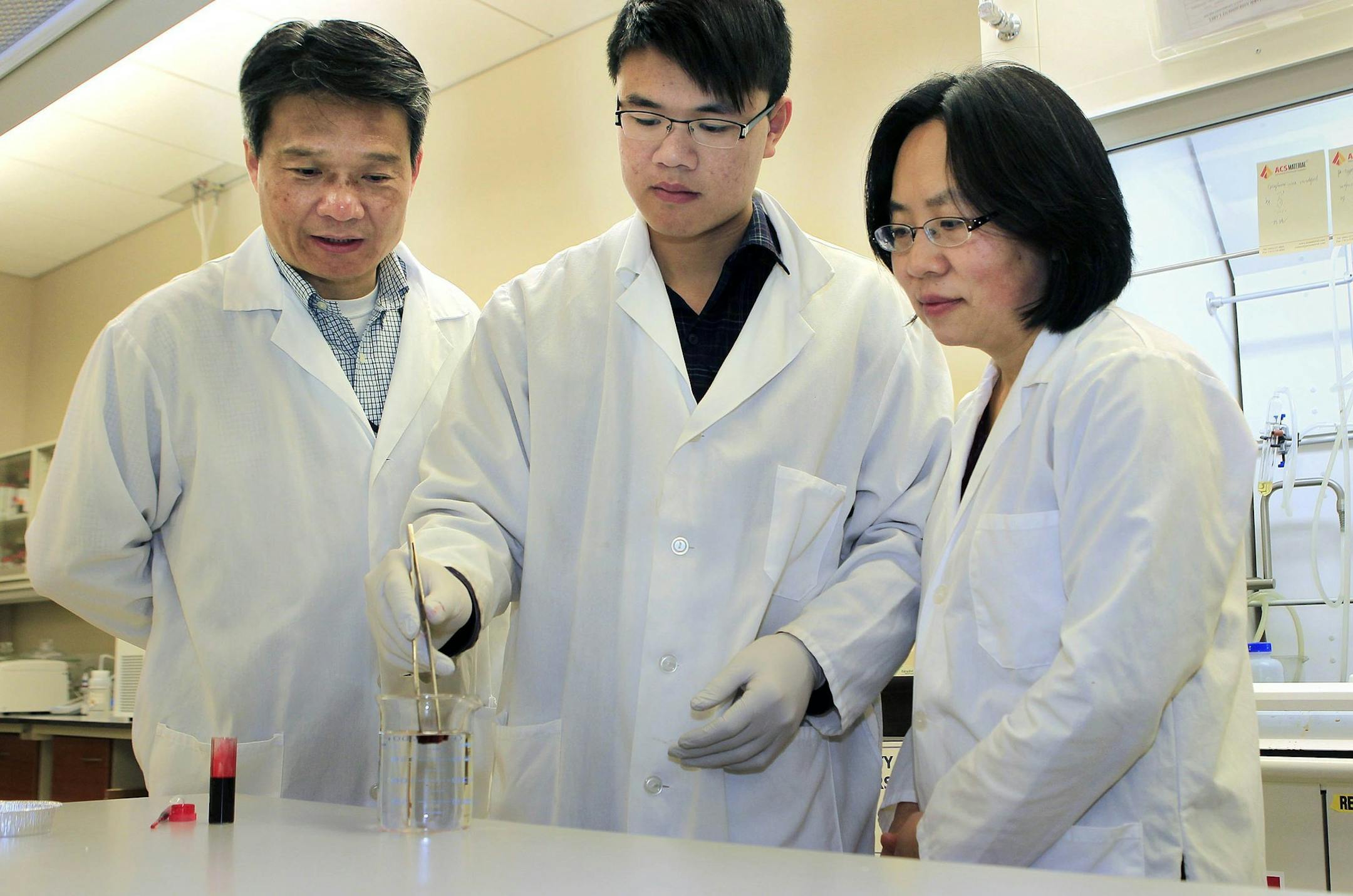 Zhi Yong Cai, project leader, from left, Qifeng Zheng, graduate student in Gong's lab; and Shaoqin "Sarah" Gong, Associate professor at UW-Madison, prepare to test their aerogel product to see if it absorbs oil, but not water, Feb. 13, 2014. (Rick Wood/Milwaukee Journal Sentinel/MCT) ORG XMIT: 1149630