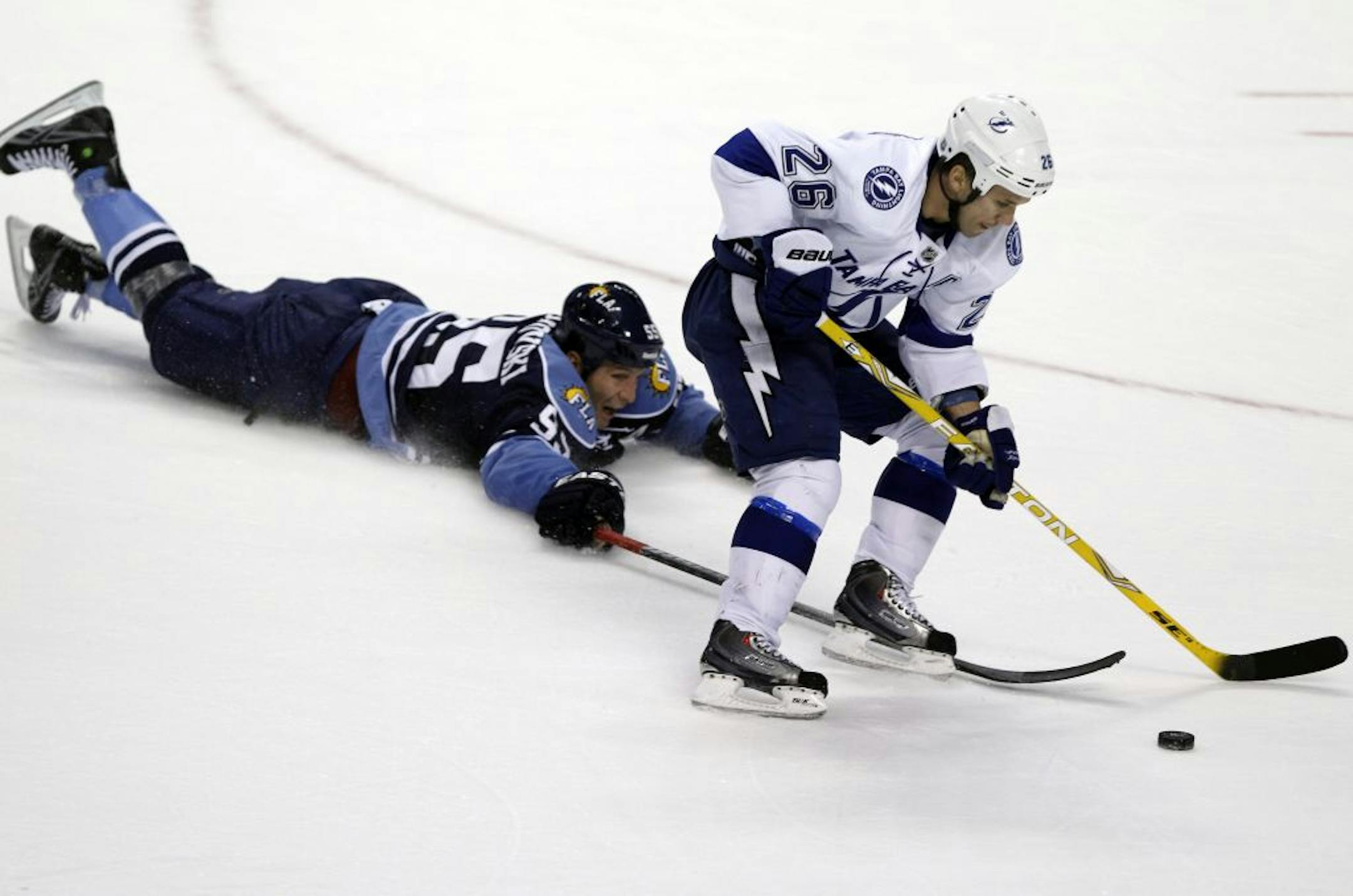 Florida Panthers defenseman Ed Jovanovski (55) slides to the ice as he fights for the puck with Tampa Bay Lightning right wing Martin St. Louis (26) during overtime in an NHL hockey game on Sunday, Nov. 6, 2011, in Sunrise, Fla. The Lightning defeated the Panthers 4-3 in a shootout.
