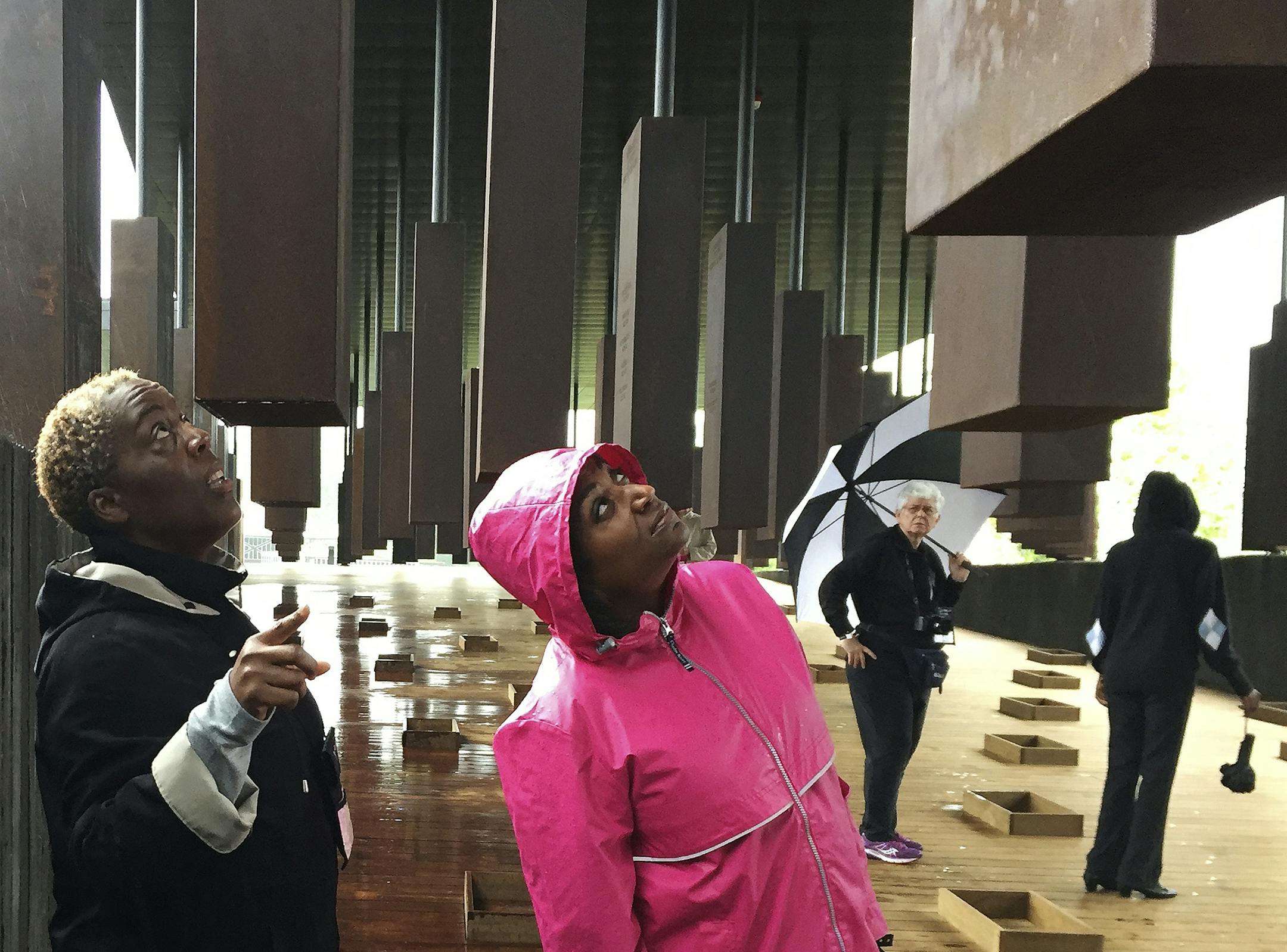 Kim McRae of Laurel, M.D., left, and Melodi McNeil, of Silver Spring, Md., look at commemorative markers listing lynching victims Thursday. April 26, 2018, at the National Memorial for Peace and Justice in Montgomery, Ala. Hundreds of people lined up in the rain to get a first look at a lynching memorial and museum that opened Thursday. (AP Photo/Beth Harpaz)