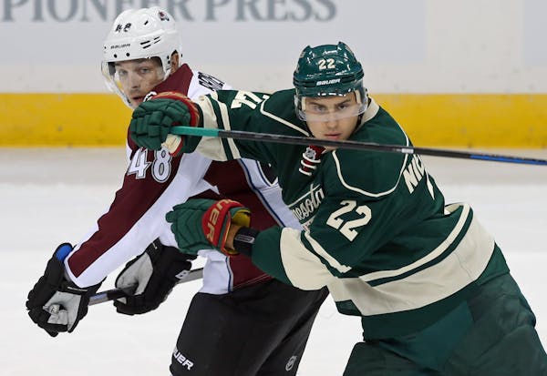 Minnesota Wild's Nino Niederreiter, right, of Switzerland, eyes the puck as he tries to keep Colorado Avalanche' s Daniel Briere at bay in the first p