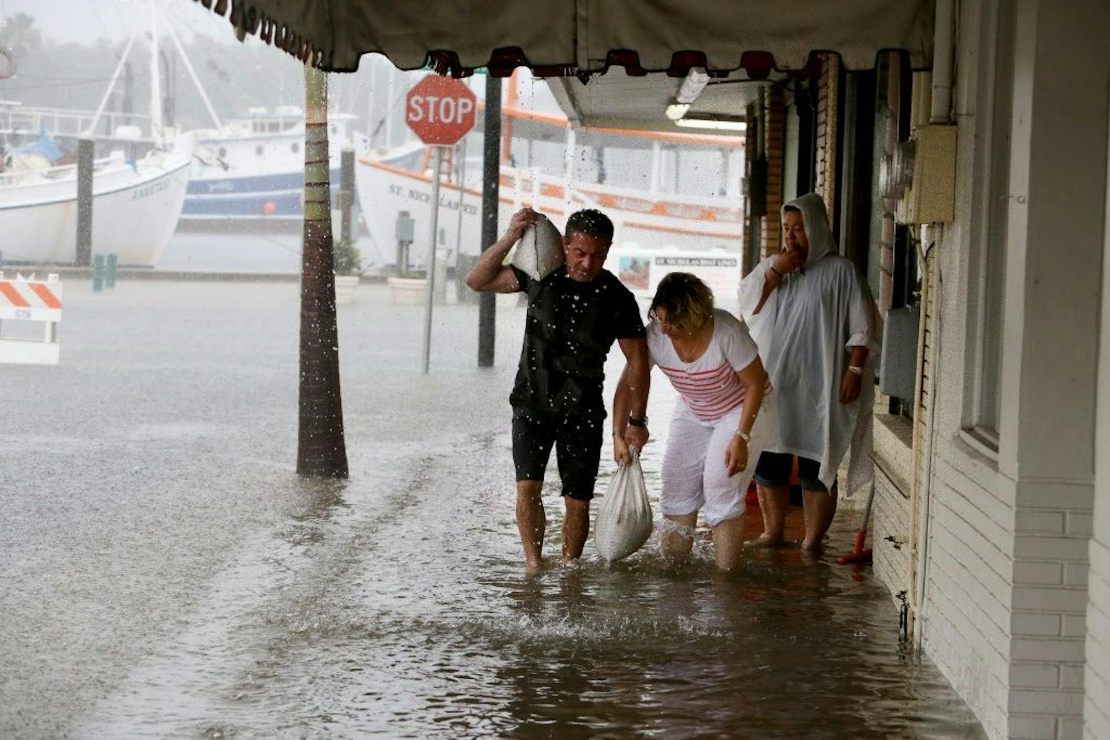 Angelo Memiakis, left, and Kelly Spiliotis work to deliver sandbags to the door jams of businesses along flooded Athens Street on Monday, June 6, 2016, in Tarpon Springs, Fla., as Tropical Storm Colin barreled up the west coast of Florida. Residents on Florida's Gulf coast filled sandbags, schools closed early and graduation ceremonies were postponed as Gov. Rick Scott declared a state of emergency with Tropical Storm Colin churning toward the state Monday, threatening serious flooding. (Douglas