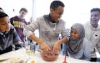 Ayub Mohamed, center, 14, gets his hands dirty mixing together ground beef with blueberries, oatmeal and spices to make healthy burgers during class a