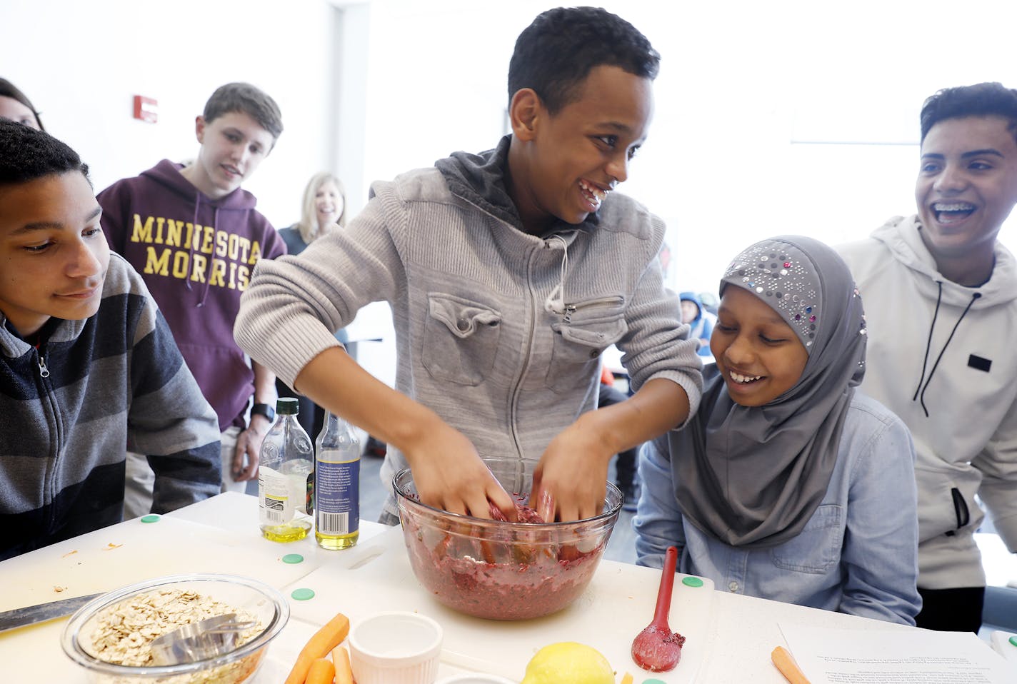 Ayub Mohamed, center, 14, gets his hands dirty mixing together ground beef with blueberries, oatmeal and spices to make healthy burgers during class as his classmates Cedrick Peters, left, 13, Jesse Lara, right, 13, and sister Amiira Mohamed, 12, look on. ] LEILA NAVIDI &#xef; leila.navidi@startribune.com BACKGROUND INFORMATION: The Teen Thrive cooking class inside the Healthy Living Kitchen at the YMCA in St. Paul on Tuesday, April 17, 2018. All the children came from Central Middle School in E