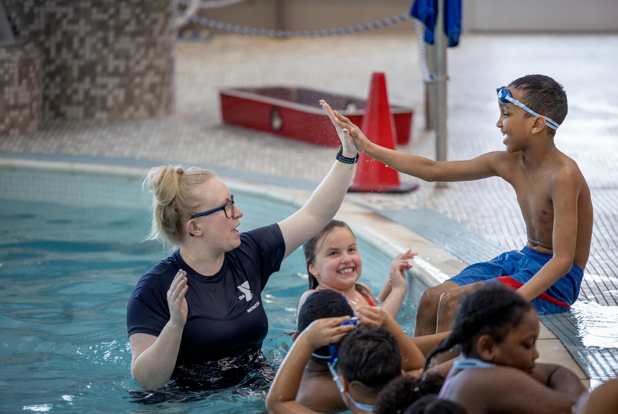 Kaitlin Pohland, the aquatics director for the St. Cloud YMCA, gives a high-five to a Madison Elementary second-grader in the pool.