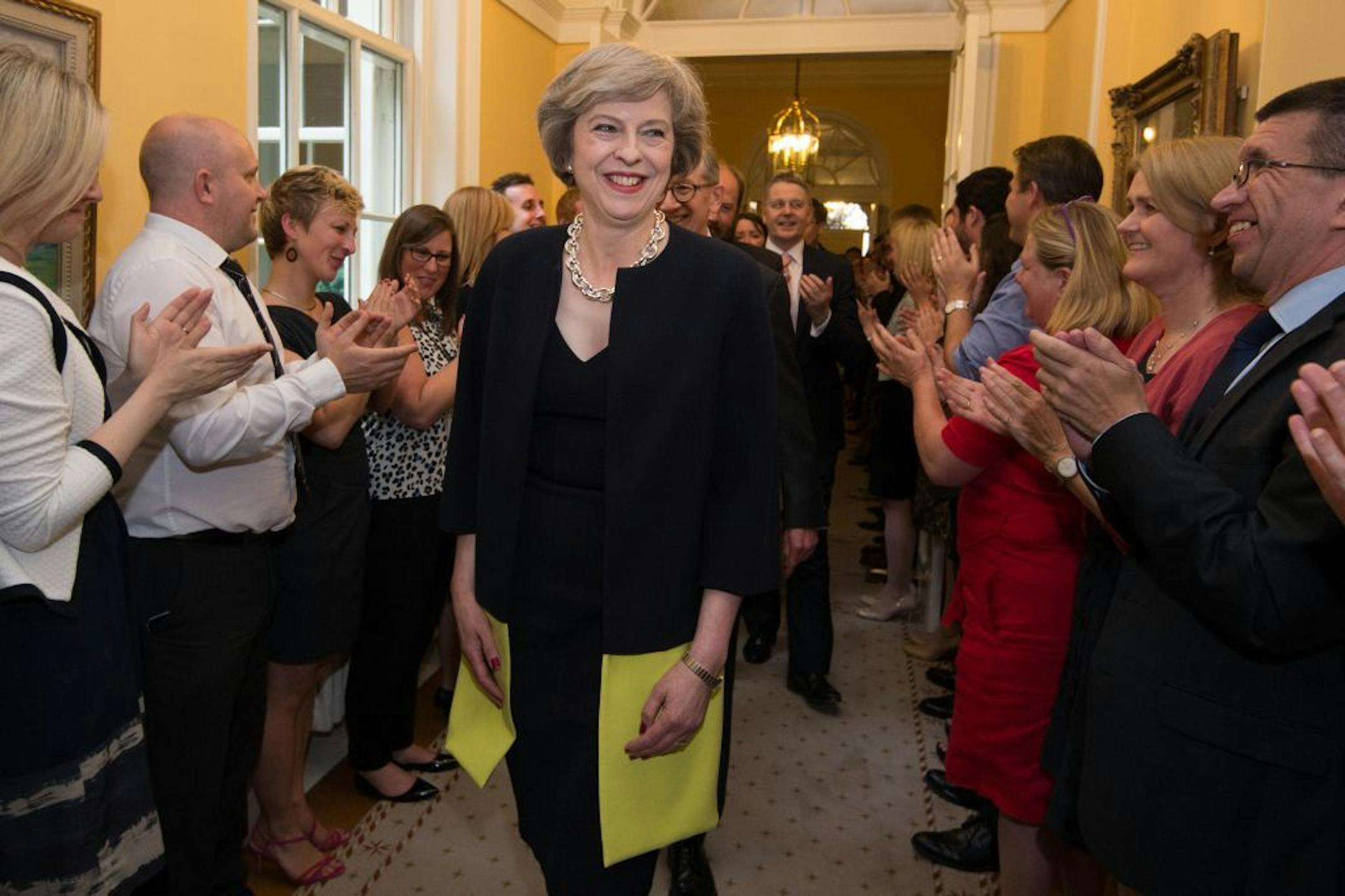 Staff clap as new Prime Minister Theresa May, followed by her husband Philip John, arrives at 10 Downing Street in London after meeting Queen Elizabeth II and accepting her invitation to become prime minister and form a new government on Wednesday July 13, 2016.