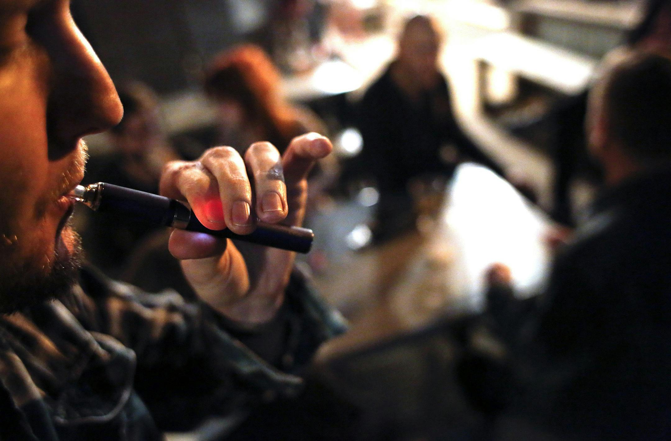 A man who did not want to be identified inhales vapor from an electronic cigarette, March 12, 2014, while socializing with friends outside Big Boss Brewery in Raleigh, N.C. (Travis Long/Raleigh News & Observer/MCT) ORG XMIT: 1150807 ORG XMIT: MIN1403252303290815