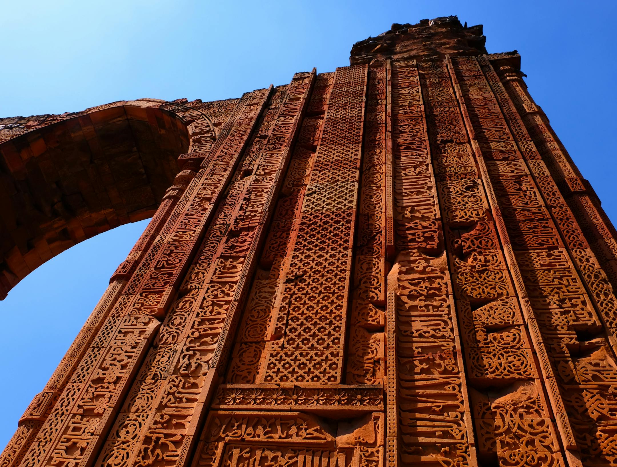 An arch at the Qutub Minar complex in Delhi was built using the ruins of Hindu temples, and Hindu motifs combine with intricate Islamic script and patterns.