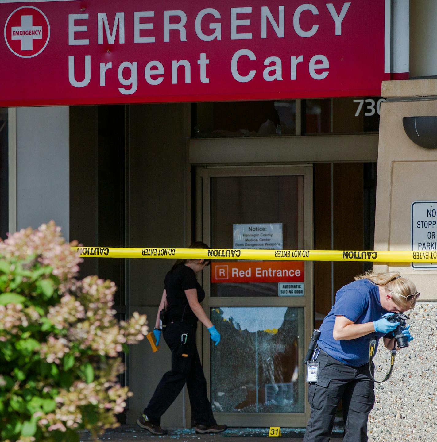 HCMC082714 * Mark Vancleave - mark.vancleave@startribune.com * Minneapolis police investigated shots that were fired at Hennepin County Medical Center in downtown Minneapolis on Tuesday, Aug. 26, 2014. [Police inspect damage to the HCMC South 8th Street entrance.]