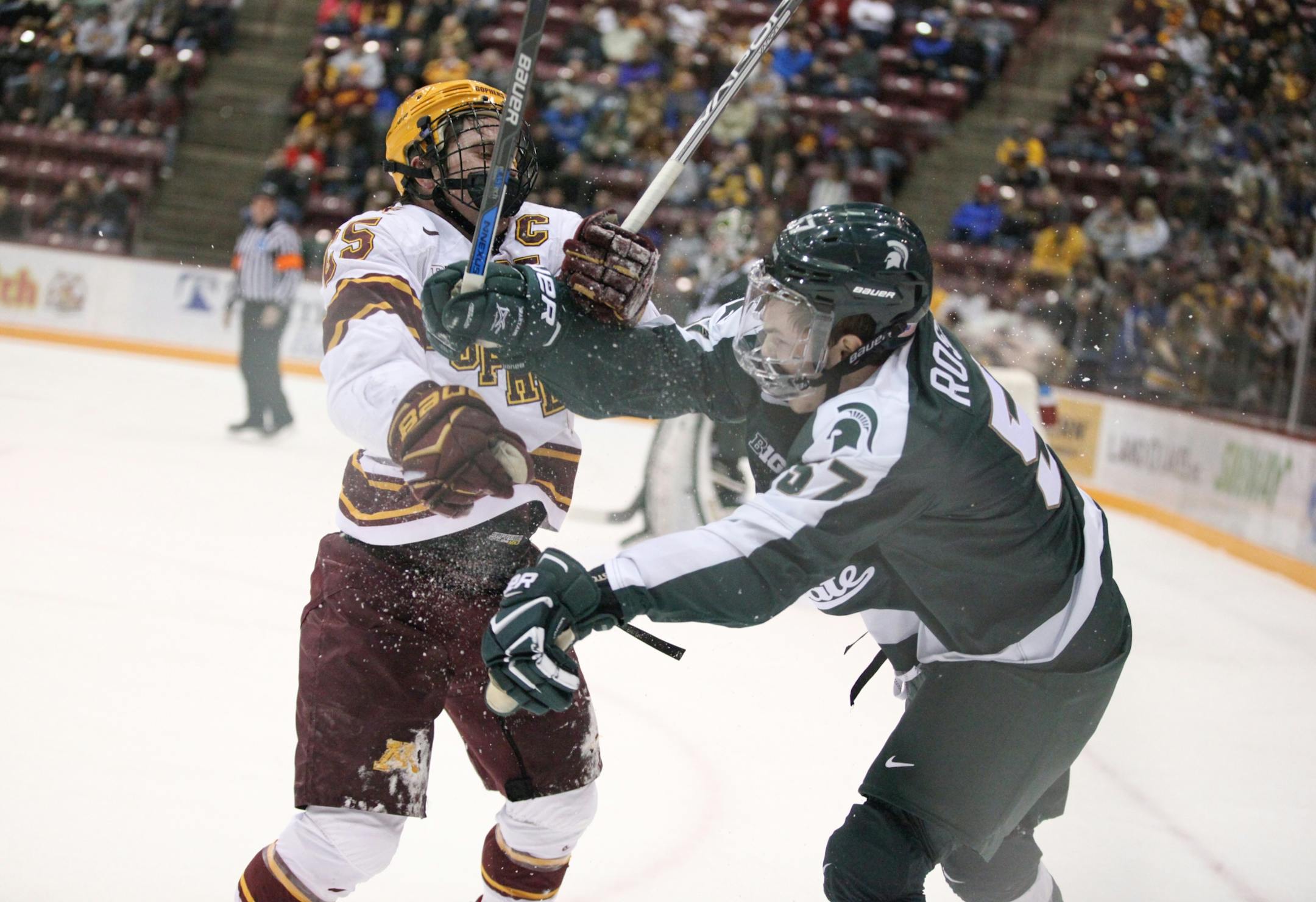 Minnesota Gophers� Justin Kloos (25) tries to check Michigan State Spartans� Jerad Rosburg (57) into the boards in the first period.