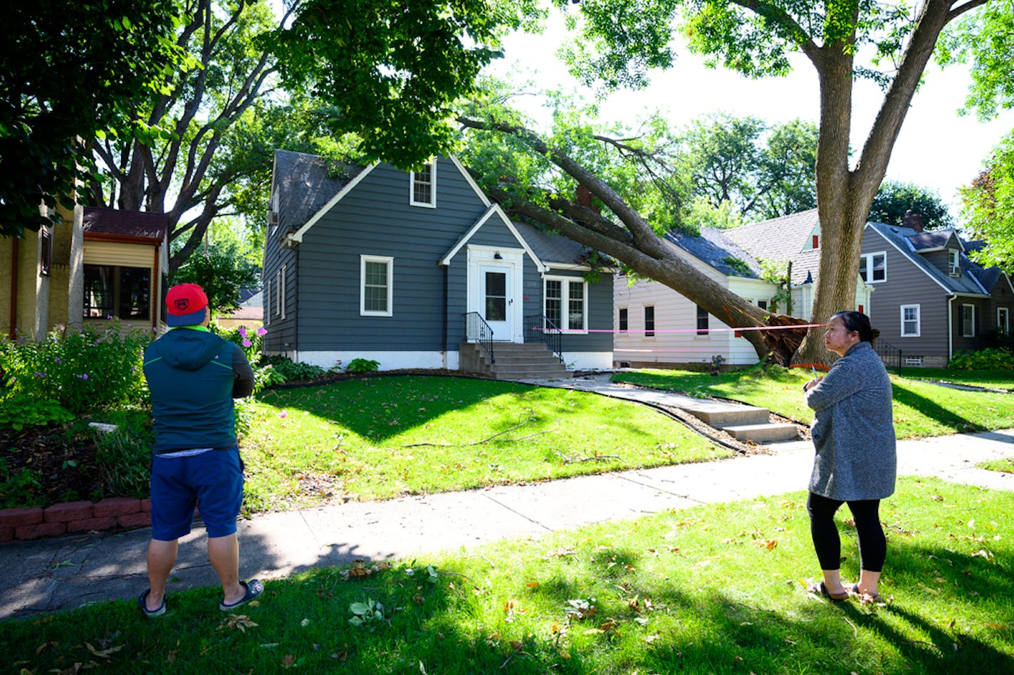 Lue Thao and Wendy Lor, of Robbinsdale, stood in front of their home, which was damaged in Friday night's storm when a tree fell on the roof.