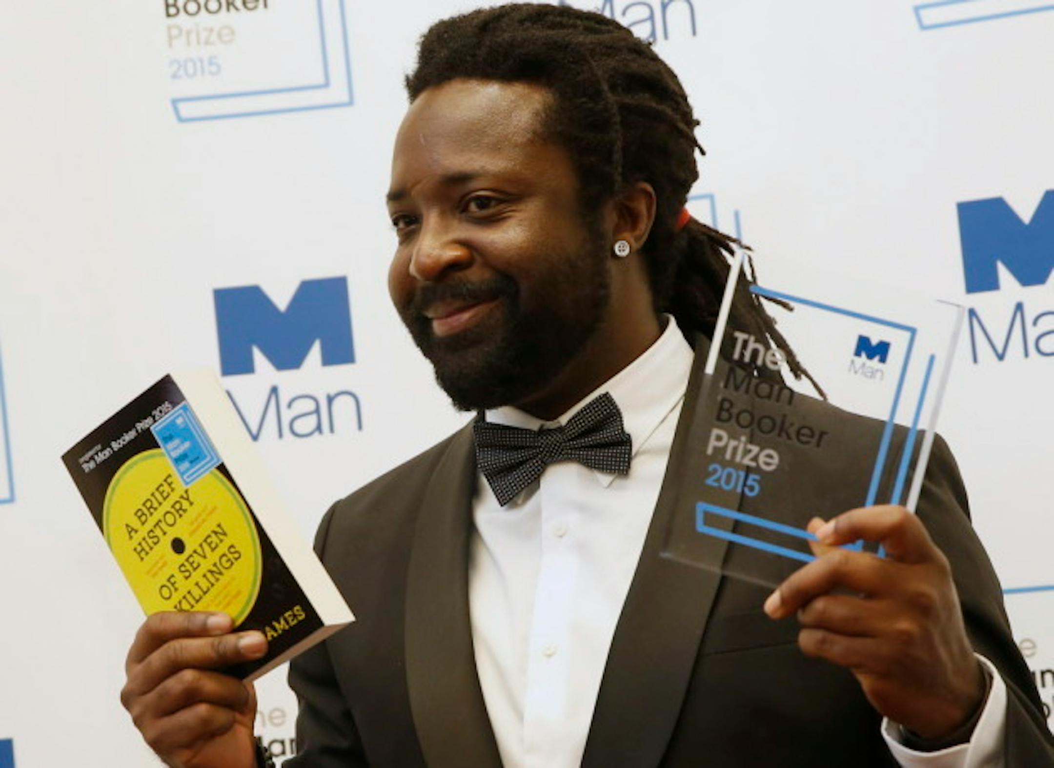 Jamaican author Marlon James holds his novel and the award after his book 'A Brief History of Seven Killings' was named as winner of the 2015 Booker Prize 2015 for Fiction, poses for photographers following the award ceremony at the Guildhall in London, Tuesday, Oct. 13, 2015.  Marlon James became the first Jamaican winner of the prestigious Booker Prize for fiction Tuesday with a vivid, violent, exuberant and expletive-laden novel based on the 1976 attempted assassination of Bob Marley.(AP Photo/Alastair Grant)