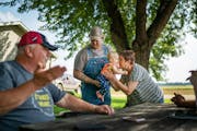 Mary Waibel cuddled granddaughter Elliott, 1, as son Jonathan Rewitzer and husband Tim, left, chatted on their farm in Courtland, Minn. Tim says trade