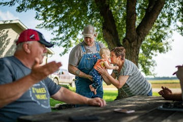 Mary Waibel cuddled granddaughter Elliott, 1, as son Jonathan Rewitzer and husband Tim, left, chatted on their farm in Courtland, Minn. Tim says trade