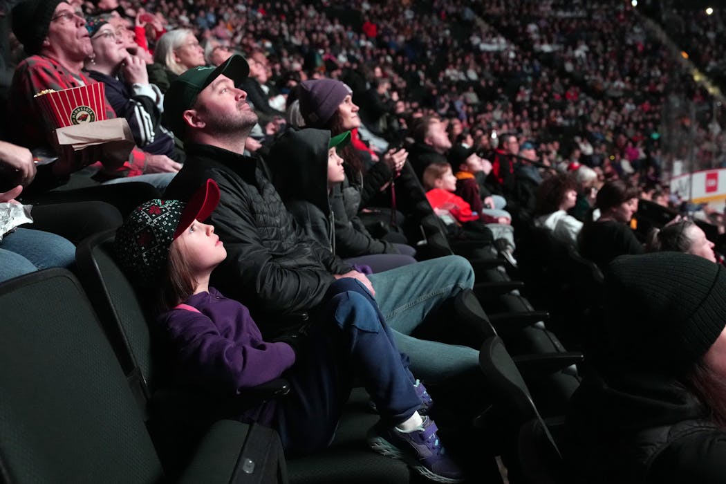 Evelyn McKenzie, 7, of Elgin, Minn., watched an intro video with her dad Kyle ahead of the first home game of the Minnesota PWHL team Saturday in St. Paul.