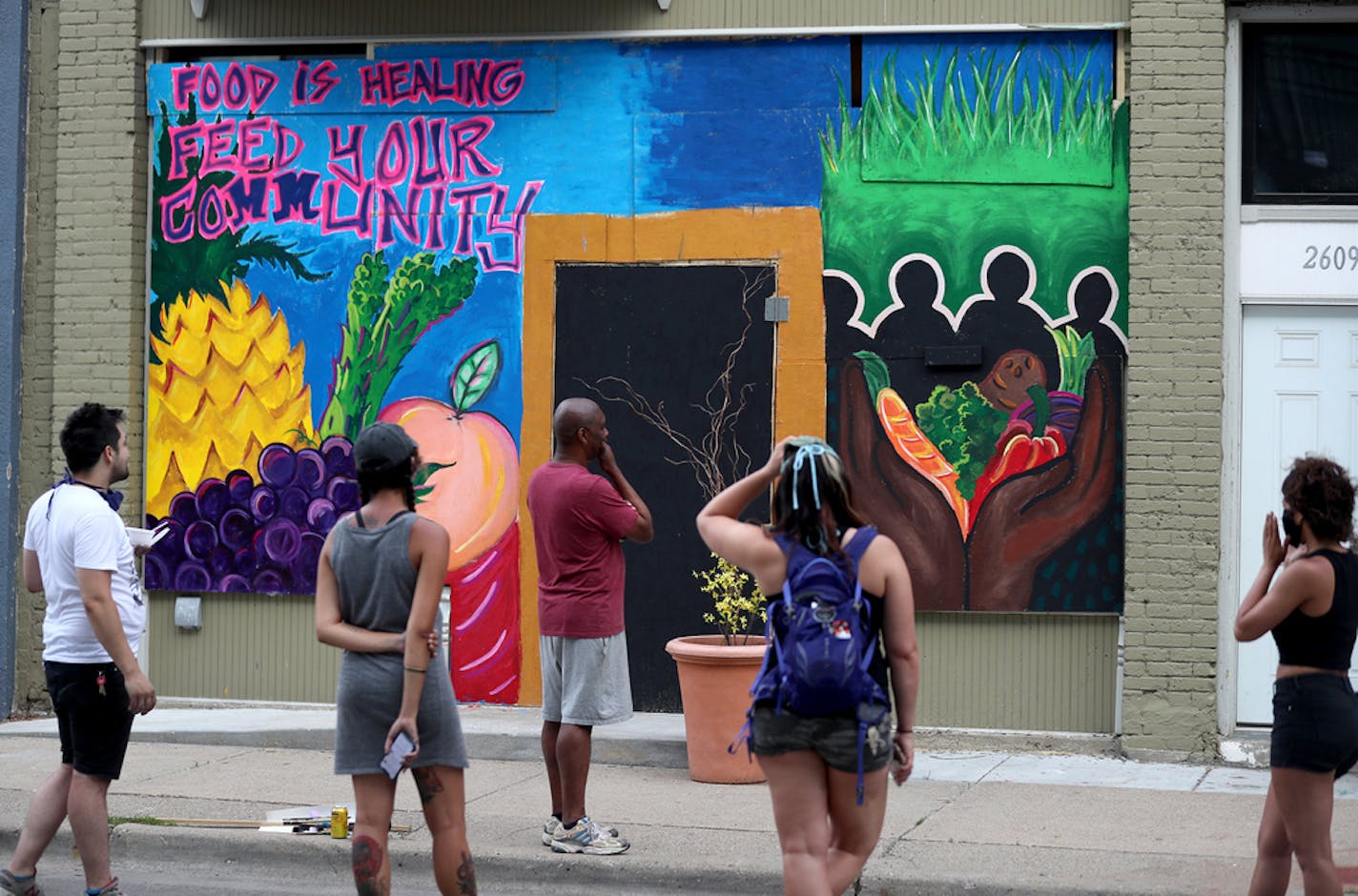 Renowned local artist Leslie Barlow and a crew painted a mural on the boarded up front of Fall Out Arts Initiative in the wake of the death of George Floyd and seen Wednesday, June 3, 2020, in Minneapolis, MN. Here, muralist crew members admired the completed mural.] DAVID JOLES • david.joles@startribune.com Murals and street art painted over boarded-up businesses offer another outlet for protest and community solidarity in the wake of George Floyd's killing.**Ryan Stopera,cq