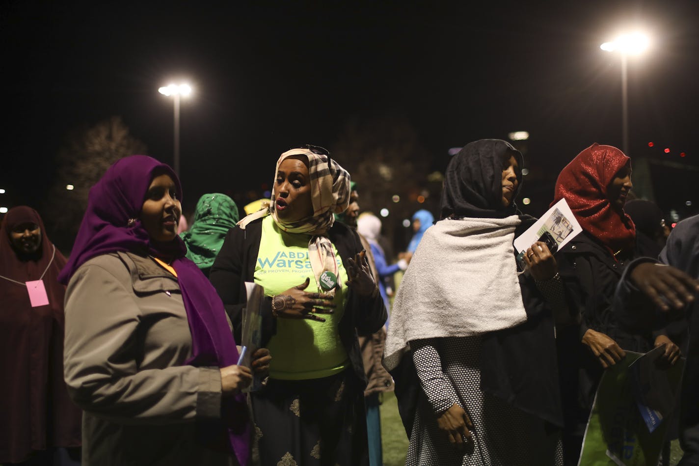 Ayanna Yusef, an Abdi Warsame supporter, in the green t-shirt, explains the caucus results to others after an official announced the results.