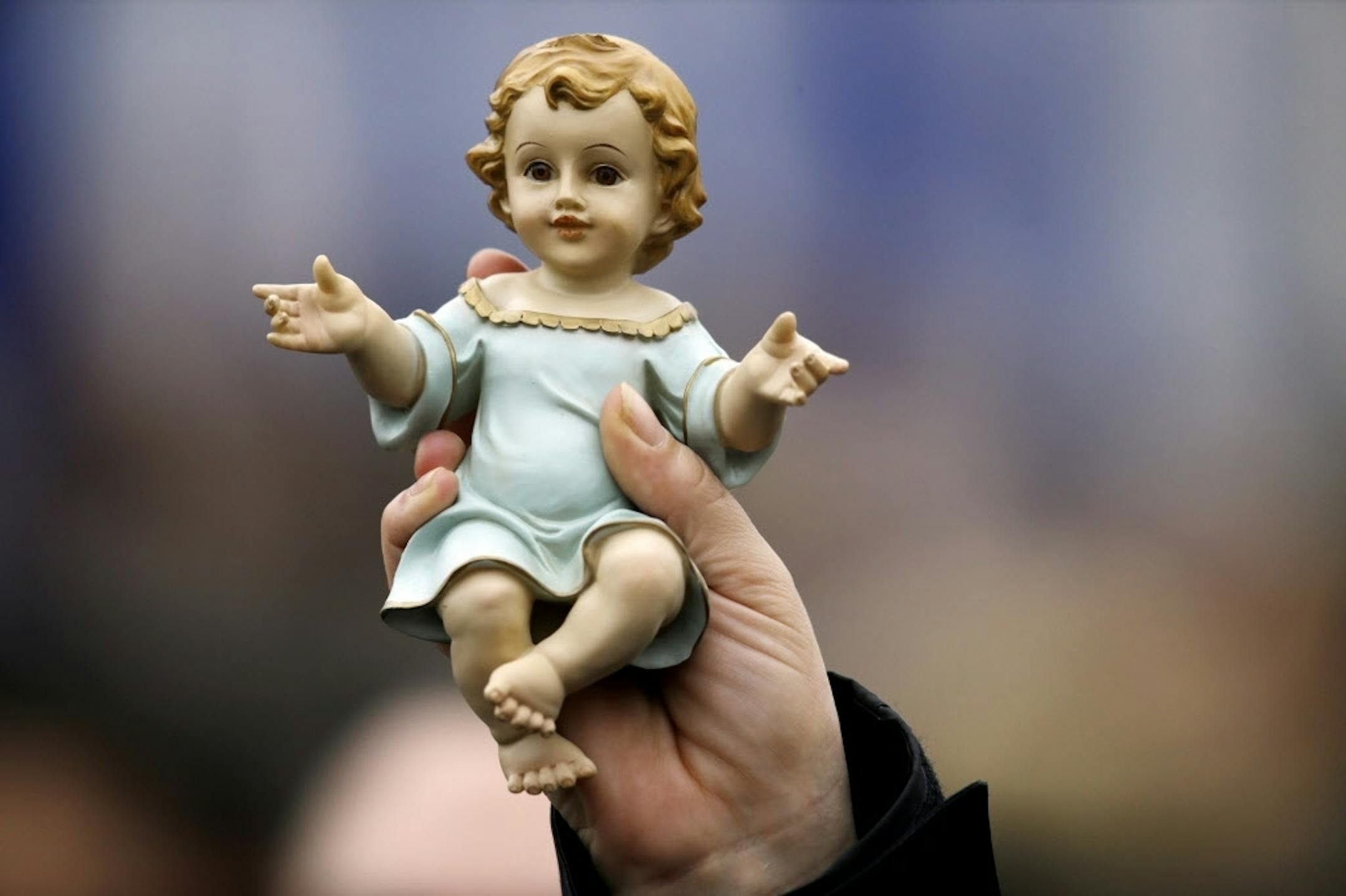 A woman holds up a statuette of baby Jesus, as she listens to Pope Francis delivering the Angelus noon prayer, in St. Peter's Square at the Vatican, Sunday, Dec. 14, 2014.