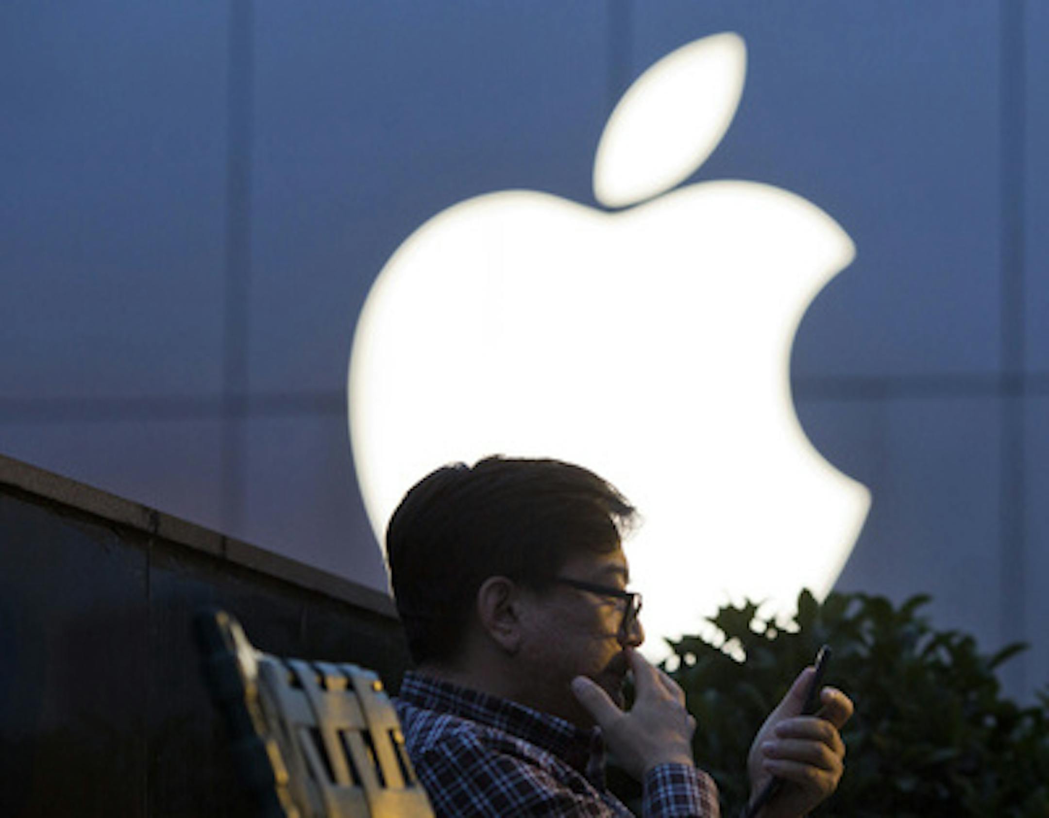FILE - In this Friday, May 13, 2016, file photo, a man uses his mobile phone near an Apple store in Beijing. Apple reports financial results Tuesday, July 26, 2016. (AP Photo/Ng Han Guan, File)